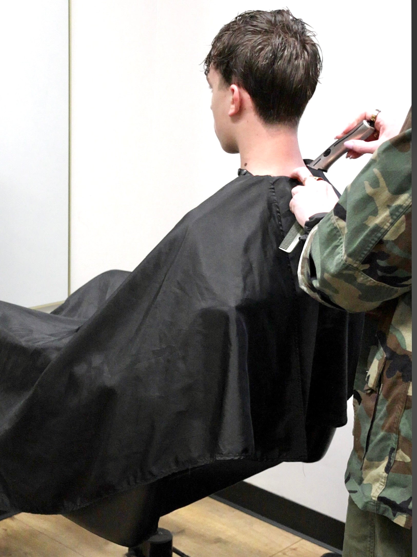 Barbering technique- showing how the salon and barber cape gives better access to lower neck trimming on clients